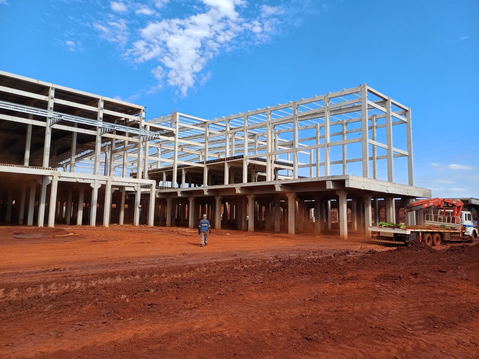 Estrutura pré-moldada de grande obra com terra vermelha e céu azul