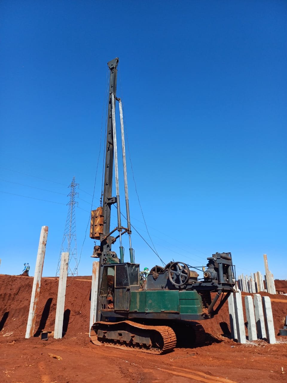 Bate-estacas sobre esteira cravando estacas de concreto pré-moldado em terra vermelha